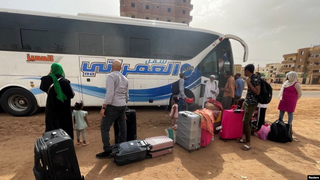 Câțiva oameni așteaptă să urce într-un autocar, în fuga lor de confruntările dintre forțele paramilitare și armată, în Khartoum, Sudan, 24 aprilie 2023.