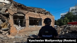 Полицаец проверува место каде станбена зграда е тешко оштетена од руски воздушен напад врз Украина, Харкив. 3 јули 2024 година.