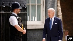  Джо Байдън гледа служител на реда, до момента в който идва да се срещне с Риши Сунак 