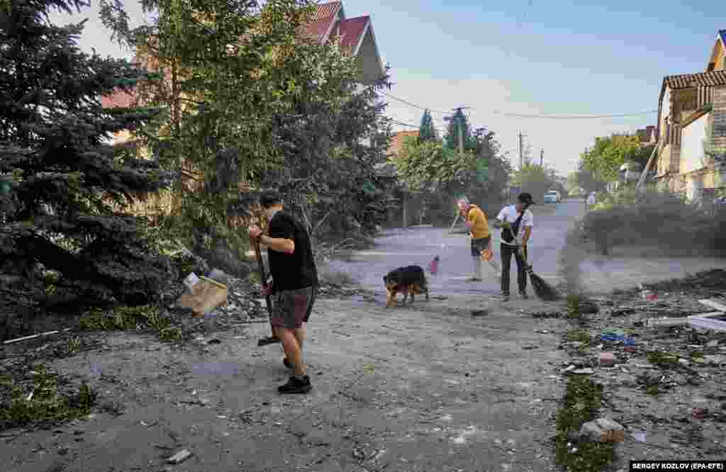 Locals clean debris following a glide-bomb attack on a private building in the village of Vilkhivka near Kharkiv in northeastern Ukraine.&nbsp;