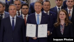 Președintele Klaus Iohannis prezintă, zâmbitor, decretele care promulgă noile Legi ale Educației. Lângă el surâd Președintele Senatului și fostul premier Nicolae Ciucă, împreună cu Ministrul Educației, Ligia Deca.