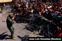 Группа нелегальных мигрантов, в основном из Венесуэлы, в мексиканском городе Сьюдад-Хуарес на границе с США, под охраной мексиканской полиции. 12 марта 2023 года