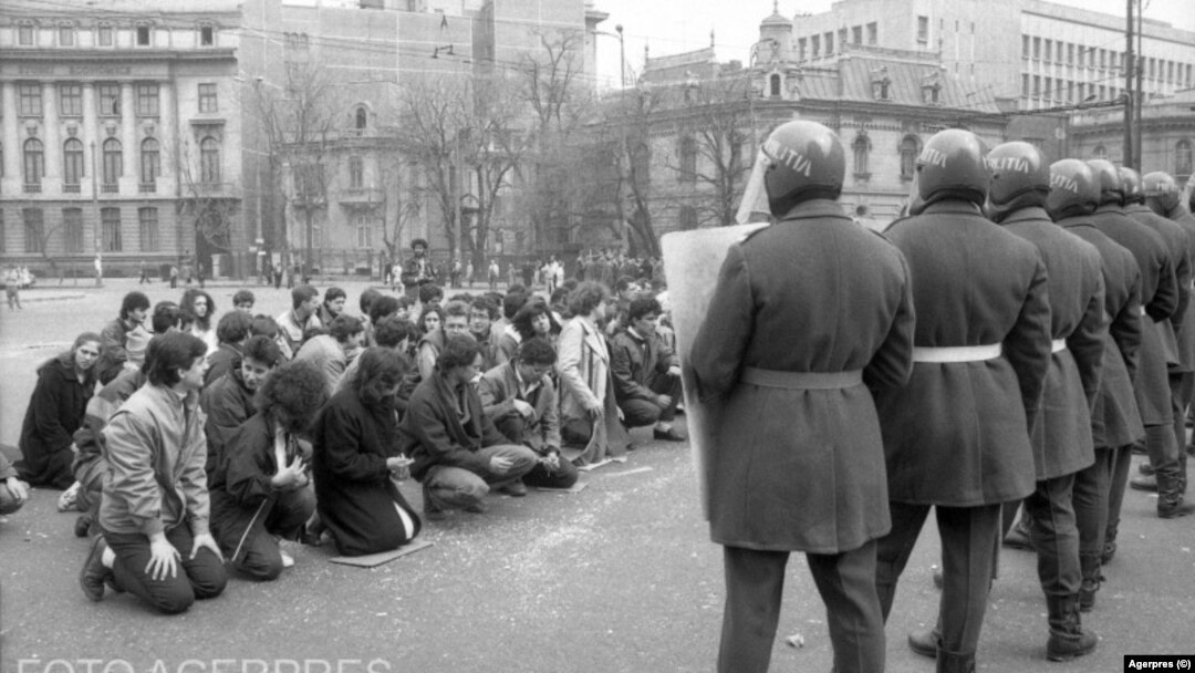 Grup de revoluționari români flancați de scutieri. București, decembrie 1989.