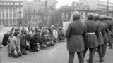 Grup de revoluționari români flancați de scutieri. București, decembrie 1989.