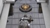 RUSSIA -- A statue of Themis, an ancient Greek Goddess of Justice, and a Russian national state emblem are seen at the entrance of Russia's Supreme Court in Moscow on November 30, 2023
