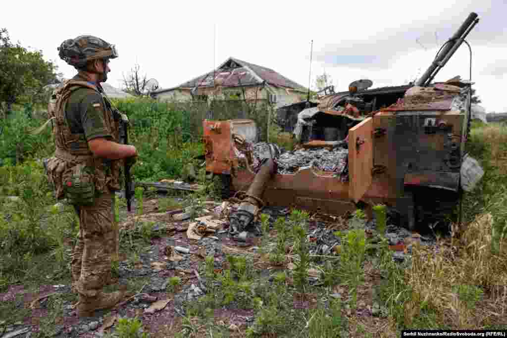 A Ukrainian soldier views the remains of a Russian armored personnel carrier.