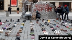 A cipők az ukrán polgári lakosság ellen elkövetett háborús bűnöket jelképezik Prága Óvárosában az invázió megindításának első évfordulóján, 2023. február 14-én