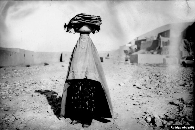 Una donna con il burqa torna a casa portando del pane per la sua famiglia e i suoi vicini a Bamiyan il 18 giugno.