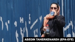 An Iranian woman drinks water during hot weather in Tehran, Iran, 22 July 2024.