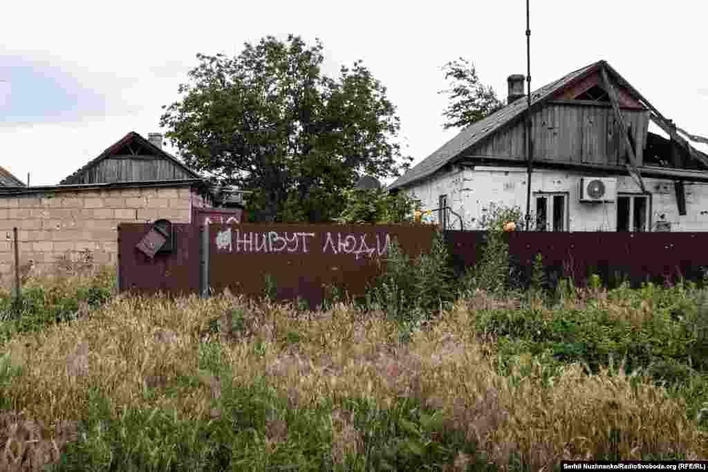 Graffiti on a fence in Blahodatne that roughly translates as &quot;People live here.&quot; According to the Ukrainian military, only two civilians are left in the village.