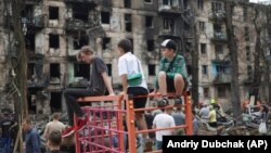 Деца гледат към мястото на руски ракетен удар, който повреди многоетажна жилищна сграда в Кривой Рог, 13 юни 2023 г.