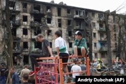 Діти дивляться на місце російського ракетного обстрілу, який пошкодив багатоповерховий будинок у Кривому Розі, 13 червня 2023 року