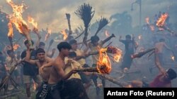 Поклонници на индуизма участват в традиционната борба с огън "Перанг апи", за която се смята, че прочиства злите сили и пази от нещастие, преди Nyepi – денят на тишината, отбелязващ Балийската нова година в Матарам, остров Ломбок, Индонезия, 10 март 2024 г.