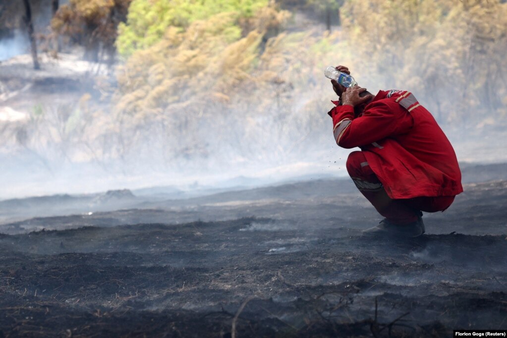Një zjarrfikës duke flladitur kokën në një zonë të shkrumbuar nga zjarret, afër Cakranit.