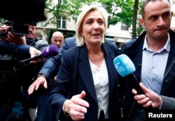 Marine Le Pen, președinta Partidului Adunarea Națională, asaltată de jurnaliști în timp ce sosește la sediul partidului, din Paris, pe 10 iunie 2024, după victoria răsunătoare a formațiunii sale la europarlamentare.