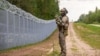 Un membru al Gărzii de Frontieră de Stat (SBG) patrulează de-a lungul gardului de la granița dintre Letonia și Belarus, în apropiere de Krivanda, în estul Letoniei, pe 8 august 2023, în timpul unei vizite a președintelui Letoniei în zonă.