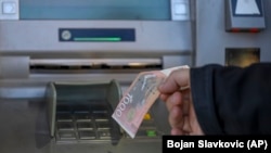 A man withdraws Serbian dinars from an ATM in the ethnically divided town of Mitrovica, in Kosovo, on January 31.