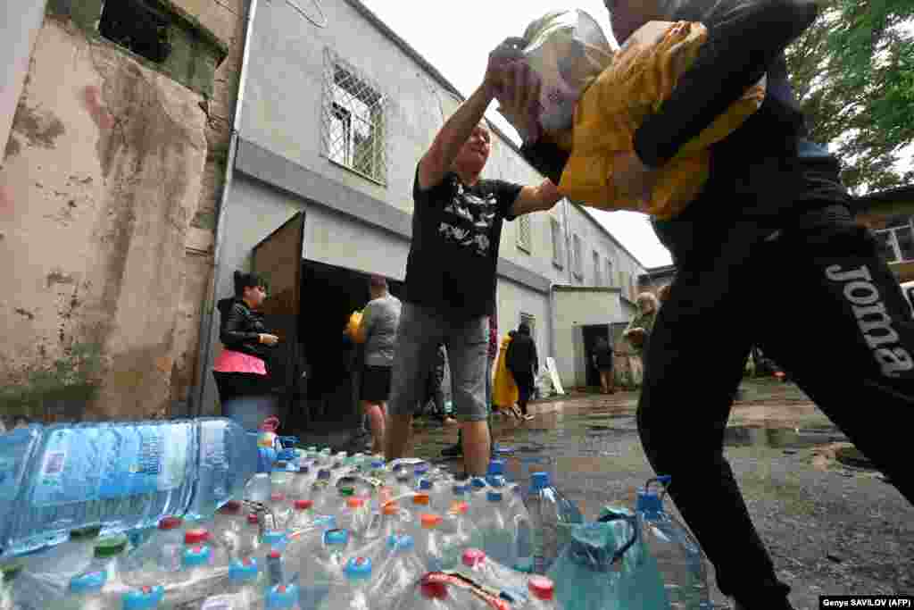 Voluntarii descarcă apă, alimente și alte bunuri donate pentru locuitorii din zonele inundate din Herson pe 11 iunie. Ruperea barajului Kahovka a inundat orașe întregi, ucigând mii de animale și distrugând comunități, rezervații naturale și terenuri agricole.