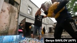 11 червня 2023 року волонтери розвантажують воду, продукти харчування та інші товари, які були надані для мешканців підтопленої території у Херсоні після руйнації греблі Каховської ГЕС.