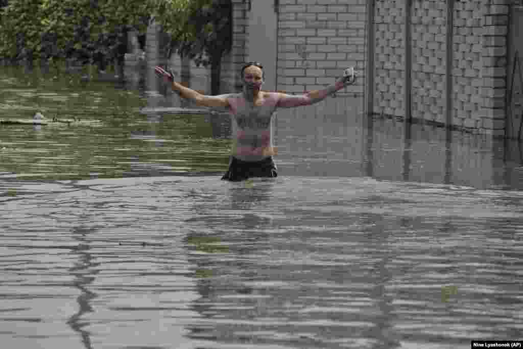 A resident gestures as he wades across floodwaters in Kherson after the Nova Kakhovka dam burst in eastern Ukraine.&nbsp;