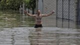 Lokalna stanovnica Tetjana drži svoje pse iznad poplavne vode dok stoji u svojoj kući u ukrajinskom lučkom gradu Hersonu 6. juna.<br />
<br />
<br />
&nbsp;
