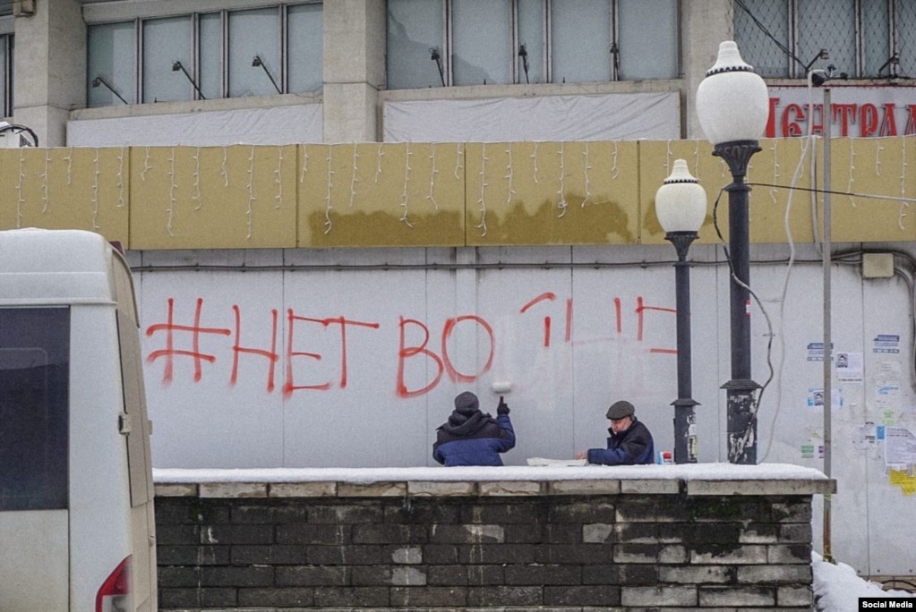 Lavoratori dipingono sui graffiti che dicono "#No alla guerra" a Lipetsk, nella Russia occidentale.