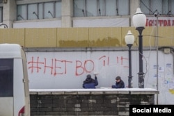 Muncitorii acoperă cu vopsea un mesaj graffiti pe care scrie „#NuRăzboiului”, în Lipetsk, vestul Rusiei.