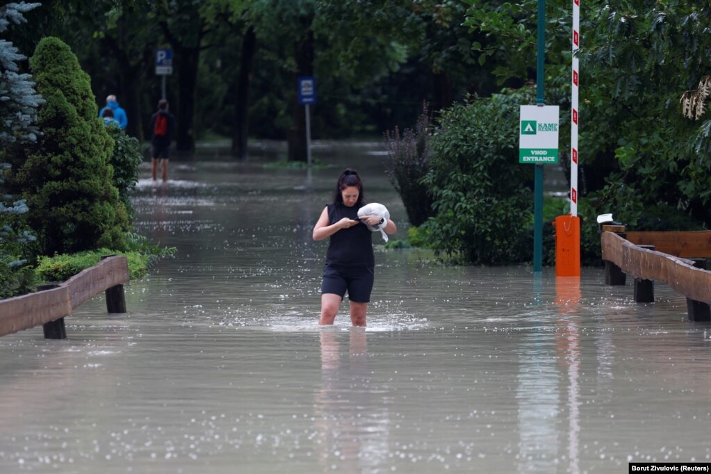 Një grua në qytetin e Kamnikut, Sllovenia veriore, duke ecur nëpër një rrugë të përmbytur nga uji. Agjencia mjedisore e Sllovenisë, ARSO, paralajmëroi në nivelin më të lartë për motin në vend, pasi në 24 orë pati reshje sa për një muaj në pjesët veriore, veriperëndimore dhe qendrore të vendit.  