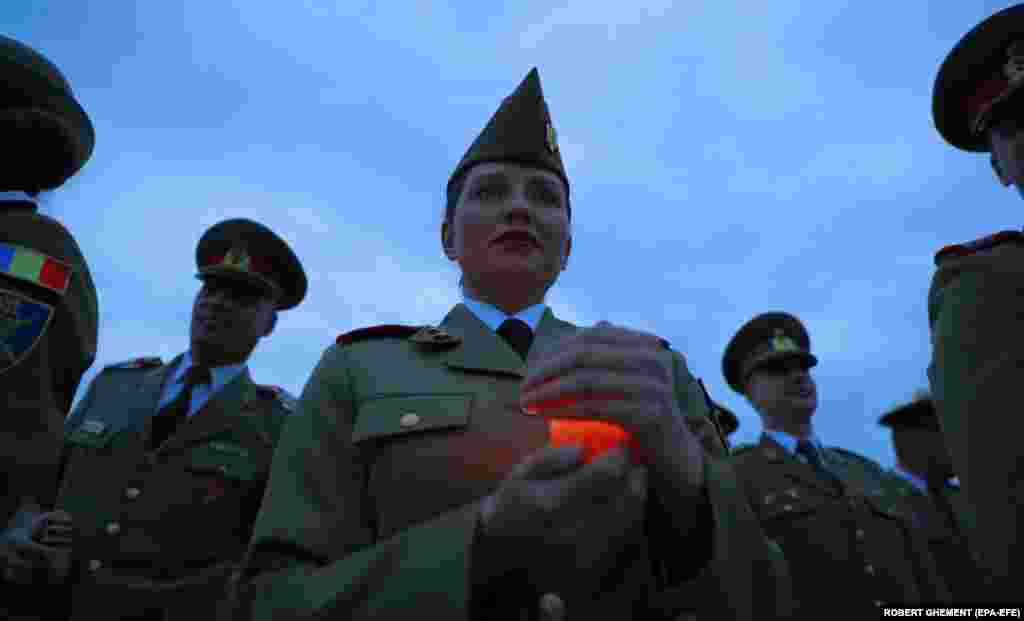 A Romanian military academy cadet holds a candle during a ceremony in front of the Unknown Hero Monument, in Carol I Park in Bucharest.