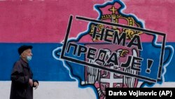 Човек поминува покрај графити на кои е прикажана мапа на Косово и српскиот грб и знаме на кое пишува: „Нема предавање!“, Белград, 26 април 2023 година