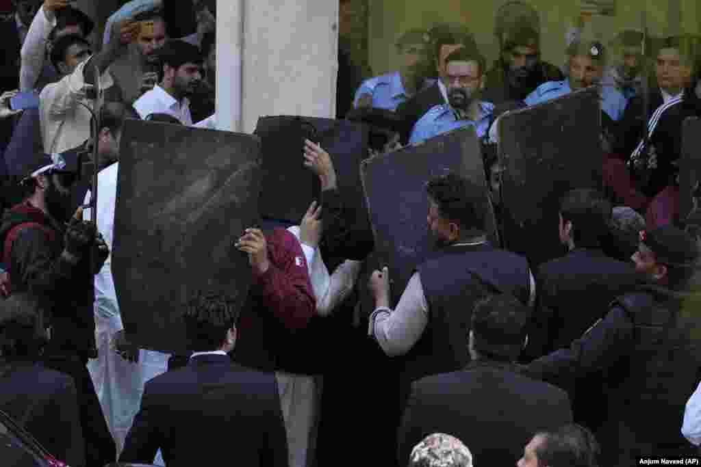 Security personnel with bulletproof shields escort former Prime Minister Imran Khan as he arrives to appear in court in Islamabad on March 27.