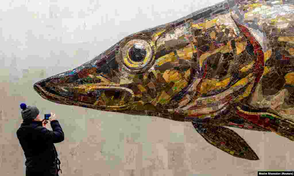 A man takes a picture of a mosaic image of a pike at the Nagatinsky Zaton station of the newly opened Big Circle Line of the subway in Moscow.