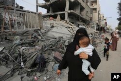 Palestinci prolaze pored ruševina zgrade uništene u izraelskom bombardovanju Pojasa Gaze u Rafi, 28. oktobra