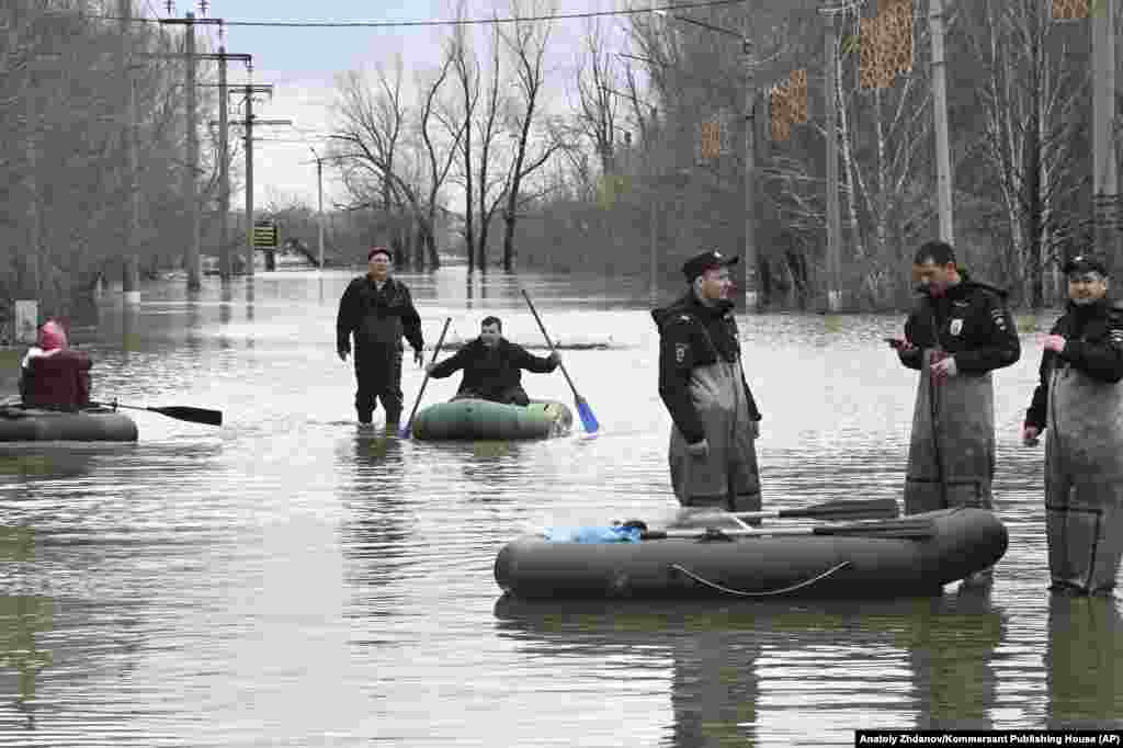 Police officers stand watch while people in Orsk rely on rubber rafts to navigate the floodwaters. &nbsp;