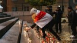 A woman wearing the white-red-white flag of the Belarusian Democratic Republic places a candle on the steps of Vilnius city hall in Lithuania on October 29.<br />
<br />
A total of 132 candles were lit in memory of Belarusian intellectuals, poets, politicians, artists, and scientists who were executed on October 29&ndash;30, 1937.&nbsp;