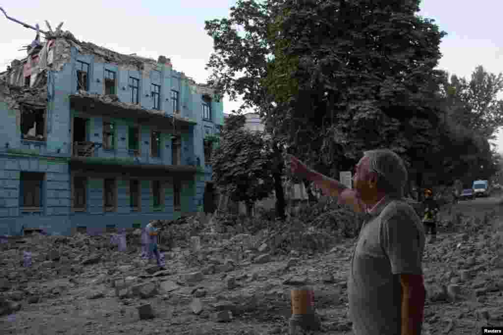 Un localnic stă lângă o clădire avariată în timpul unui atac cu rachete rusești, pe fondul atacului Rusiei asupra Ucrainei, în Odesa, Ucraina, 23 iulie 2023