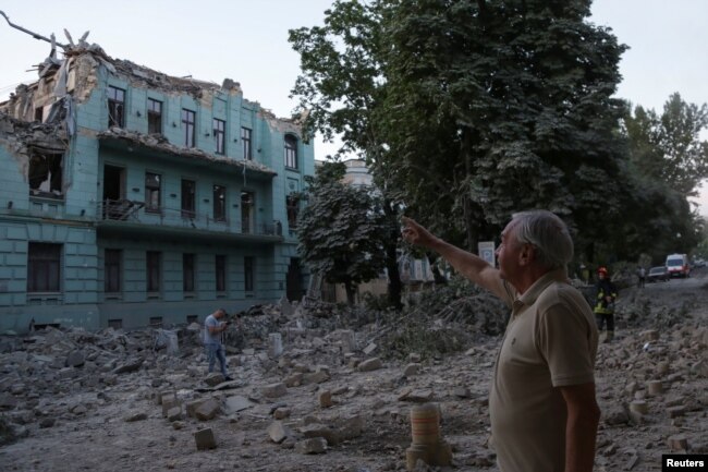 Një banor vendës duke qëndruar para një ndërtese të dëmtuar nga një sulm rus me raketë në Odesë, më 23 korrik 2023.