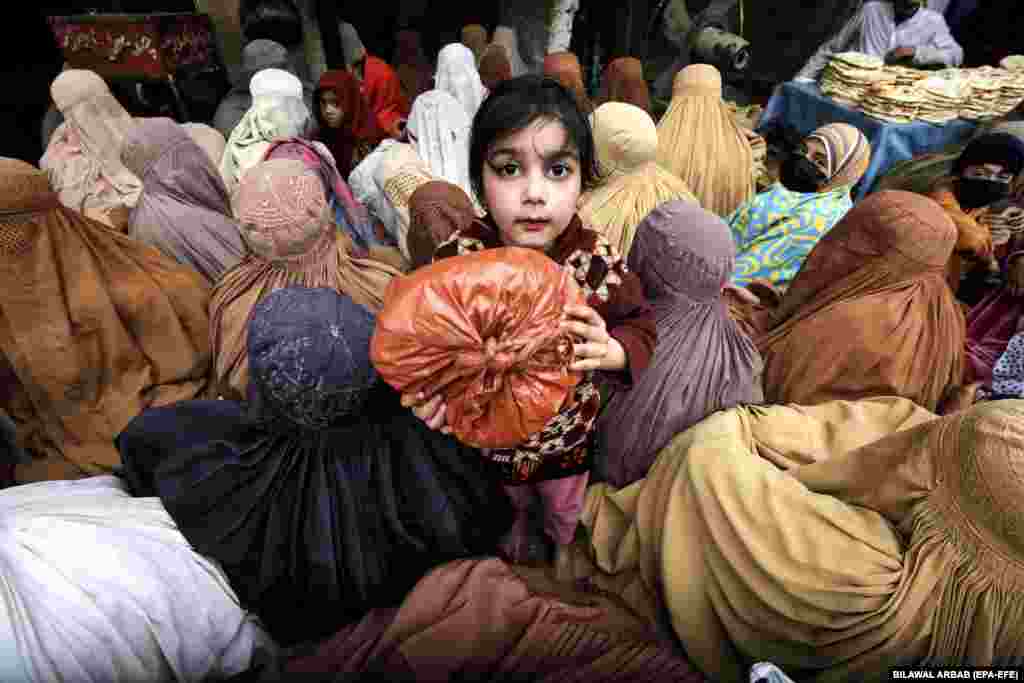 Žene i djeca čekaju na hranu koju dijele mještani kako bi prekinuli ramazanski post u Pešavaru, Pakistan.