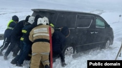 Rescuers try to remove a car stuck in the snow amid heavy blizzards in Kazakhstan