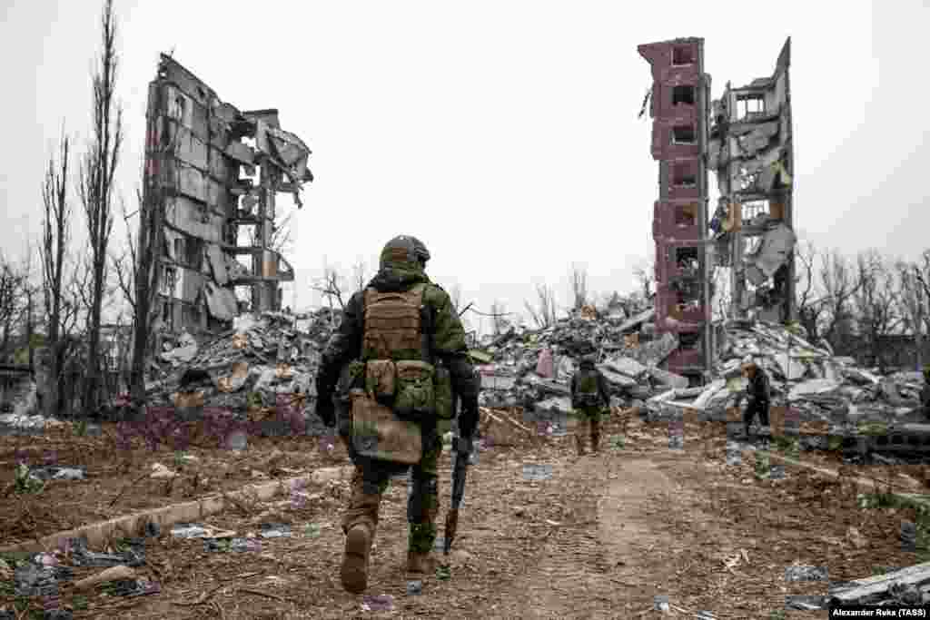 Российские военные приближаются к разрушенному жилому дому в Авдеевке, городе в Донецкой области Украины. Фото снято 22 февраля. Это один из первых снимков Авдеевки после захвата города российскими войсками