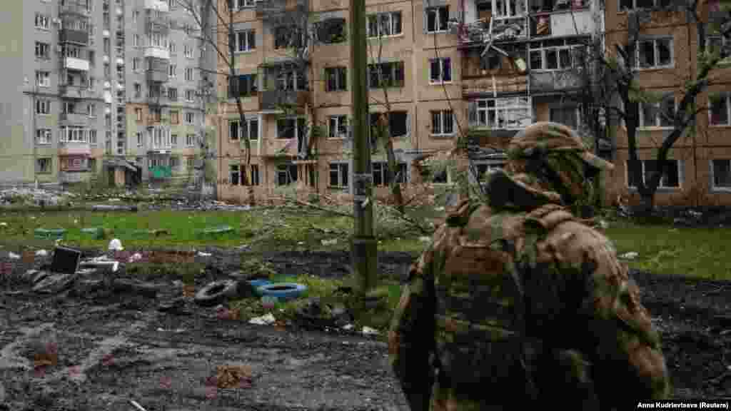 Egy ukrán katona járőrözik a romokban álló lakóépületek közelében Bahmutban