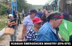 A handout photo from the Russian Emergency Ministry's press service shows people entering buses as they are evacuated from border settlements of the Kursk region on August 13.