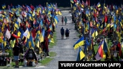 People walk through the cemetery of Lychakiv as they pay tribute to fallen soldiers during the Day of Remembrance of the Defenders of Ukraine, in Lviv on August 29.