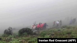 Salvatorii cară trupuri neînsuflețite la locul prăbușirii elicopterului în care se afla președintele Iranului, luni, 20 mai.