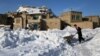 An Afghan man pushes a wheelbarrow following heavy snowfall in Ghazni Province early last month. 