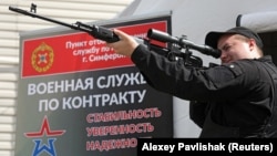 Чоловік тримає макет снайперської гвинтівки СВД у мобільному пункті призову на військову службу за контрактом до російської армії у Сімферополі, Крим, 15 квітня 2023 року