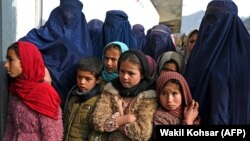 زنان برقع پوش افغان با کودکان در ۲۵ فبروری ۲۰۲۴ در فیض آباد در ولایت بدخشان منتظر دریافت بسته‌های زمستانی از یونیسف هستند.