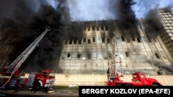 Украински пожарникари гасят пожар на мястото на ракетно нападение срещу промишлена сграда в Холоднохирския район на Харков.