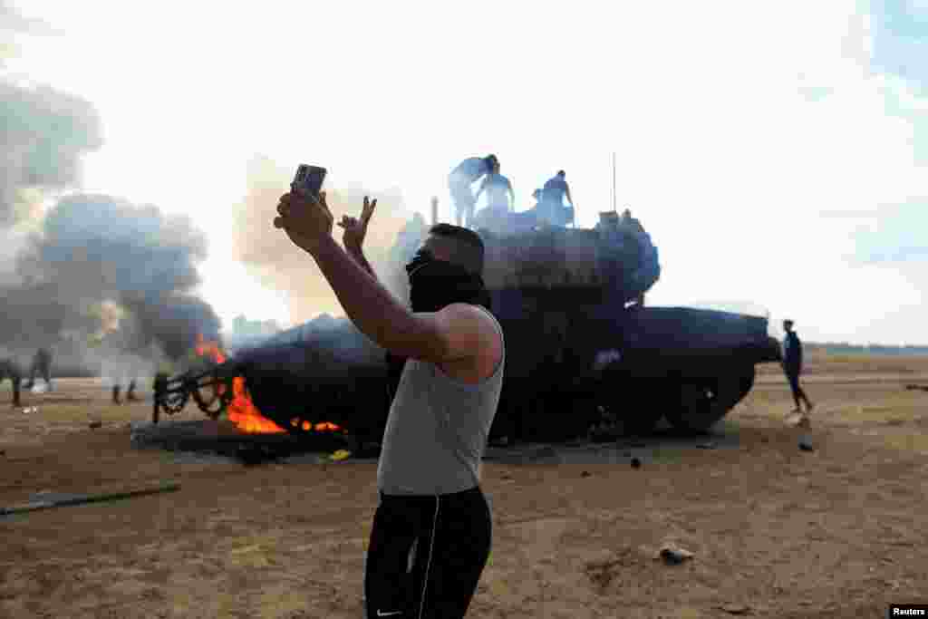 Un palestinian își face un selfie în fața unui vehicul militar israelian în flăcări, după ce acesta a fost lovit de oameni înarmați palestinieni care s-au infiltrat în zonele din sudul Israelului,&nbsp;