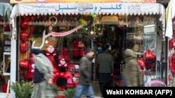 Afghan men walk past a gift shop along Flower Street in the Shar-e Naw area of Kabul on February 14. 